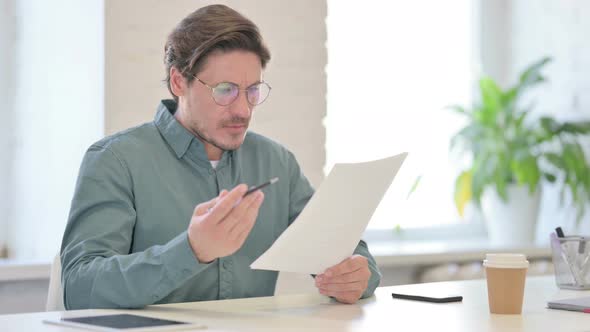 Middle Aged Man Reacting to Loss While Reading Documents
