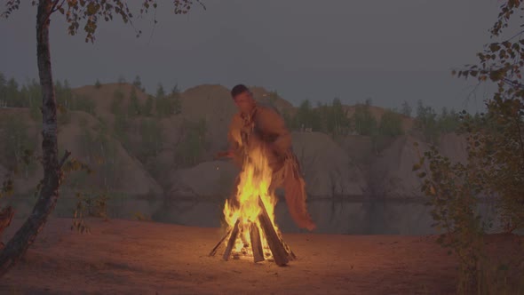 A Shaman with a Drum Jumps in Around the Fire in Clothes for the Ceremony