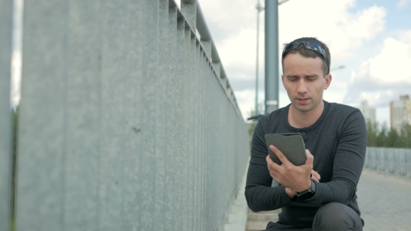 Outdoor Portrait Of Modern Young Man With Digital Tablet. Railing Of The Bridge, Near The Road 