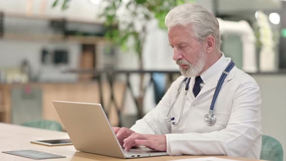 Senior Old Doctor Working on Laptop in Office