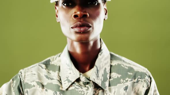 Androgynous man in camouflage uniform against green background