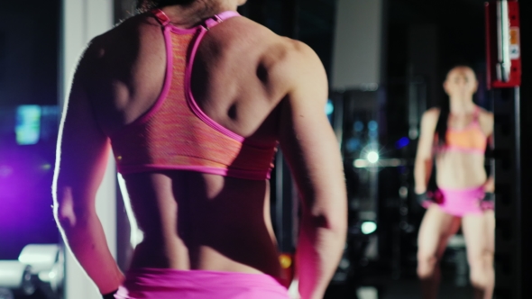 Athletic Woman, a Professional Bodybuilder Posing In Front Of a Mirror, Shows Trained Muscles Of The