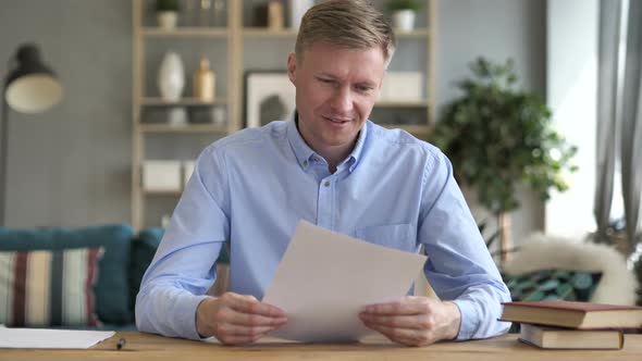 Businessman Excited After Reading Contract Papers at Work