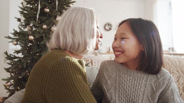 Happy Asian Girl Hugging Grandmother on Christmas at Home