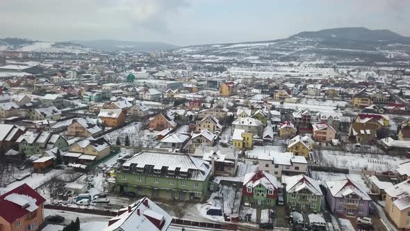 Flying over suburbs of city with colorful houses and snow covered roofs, Bistrita, Romania