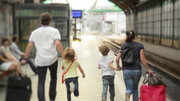 Young Family Of Two Spouses, Son And Daughter, Running To Catch The Train Before It Leaves