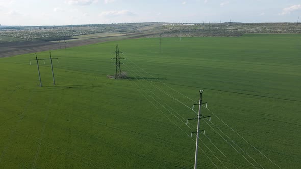 Aerial View of High Voltage Lines and Power Pylons in a Flat and Green