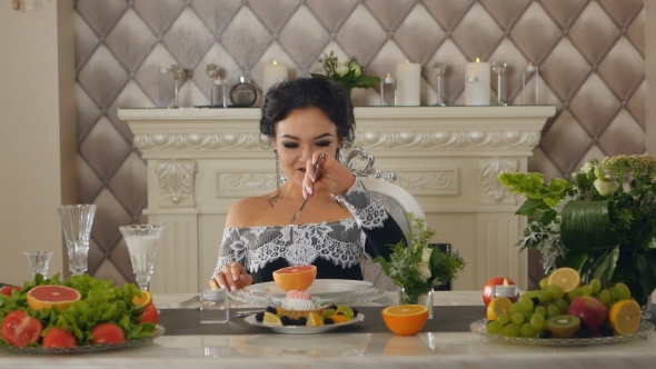 Woman Sitting At a Table Posing With a Grapefruit In The Hands