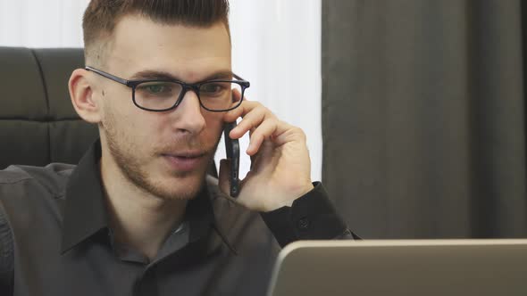 Man talking on phone in office, close up view.