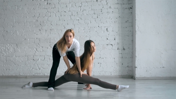 Yoga Trainer Helps Female Student to Stretch Legs and Do the Splits