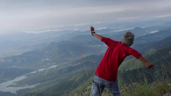 A man throwing a rock down from a cliff.