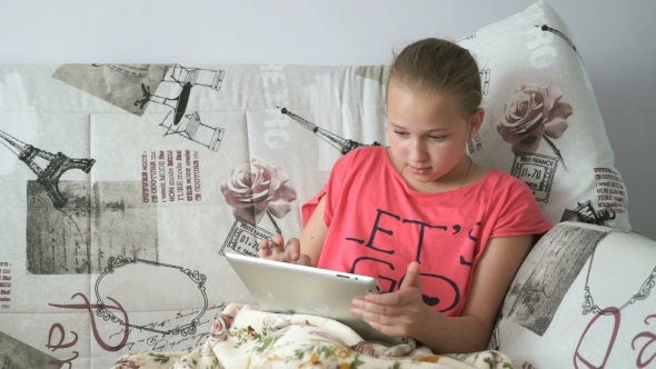 Child Reading a Digital Tablet Lying On The Bed