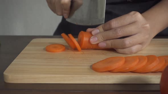 woman making healthy food and chopping carrot on cutting board in the kitchen.