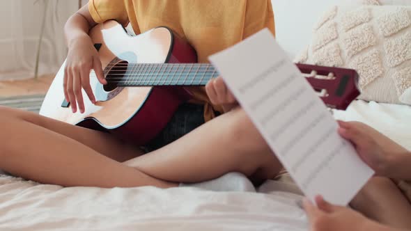 Woman Teaching Music Lessons to Boy Sitting on Bed at Home