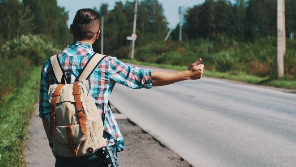 Back Side of Young Boy With Backpack Hitchhiking at Road in Summer Sunny Day.