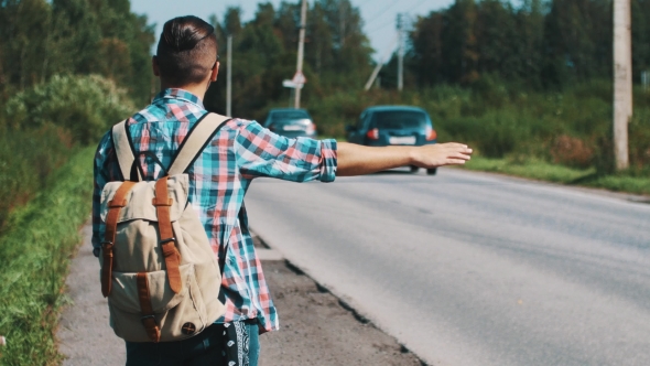 Young Boy With Backpack Hitchhiking At Road In Summer Sunny Day. Thumb
