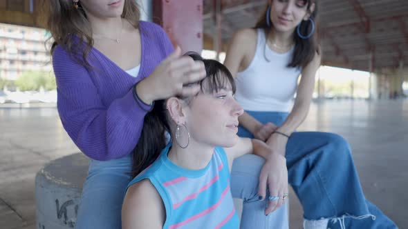 Close View of Young Women Sitting Talking and Fixing Hair Outdoors