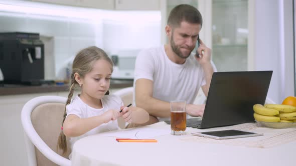 Relaxed Little Girl with Pigtails Drawing and Showing Picture to Blurred Busy Father Talking on the