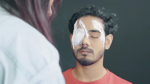 Man with prosthetic insert on his eye waiting for make up artist to finish his Halloween mask in cos