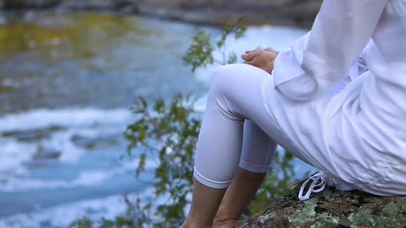 Young Woman Relaxing Near the Flowing River