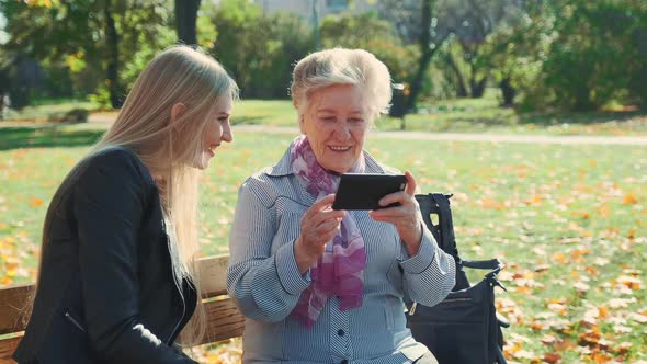 Elder Grandmother Showing Her Granddaughter Photos on Smartphone