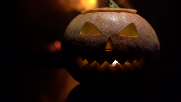 Creepy halloween pumpkin near a fireplace. Fire on the background.