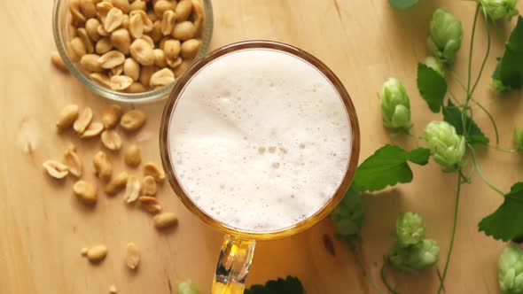 Top View of Beer with Foam and Salty Peanuts and on Wooden Table