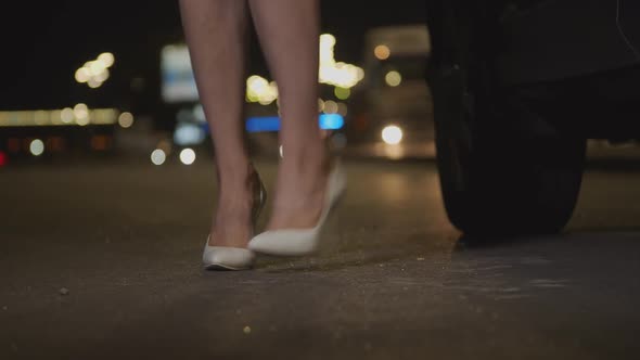 Woman's Legs Waiting Impatiently Near Car at Night