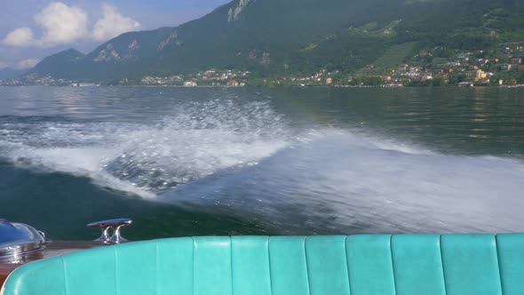 Water spray comes from a classic luxury wooden runabout boat on an Italian lake.