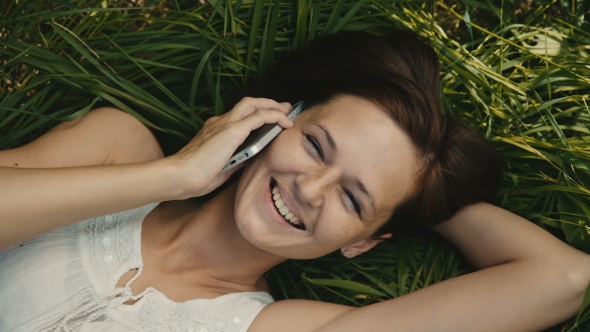 Beautiful Woman Lying On The Grass Talking On The Phone And Smiling