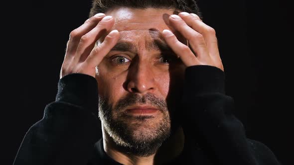 Frightened Man Holding Head Isolated on Black Background, Horror Scene, Close-Up