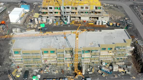 Aerial View Of Ongoing Construction Of Buildings With Yellow Tower Cranes At Daytime.