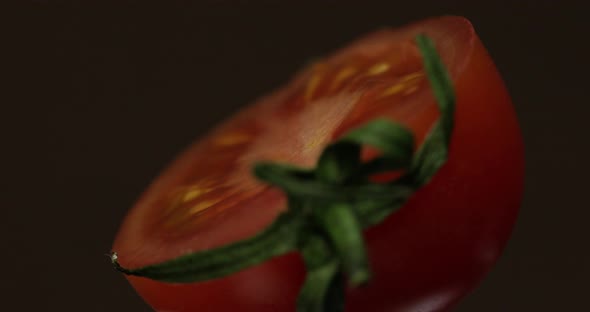 Rotate of the Halves of Fresh Ripe Cut Tomato on a Dark Background