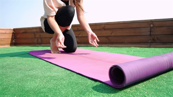 Young Woman Unfolding Mat For Yoga Practice