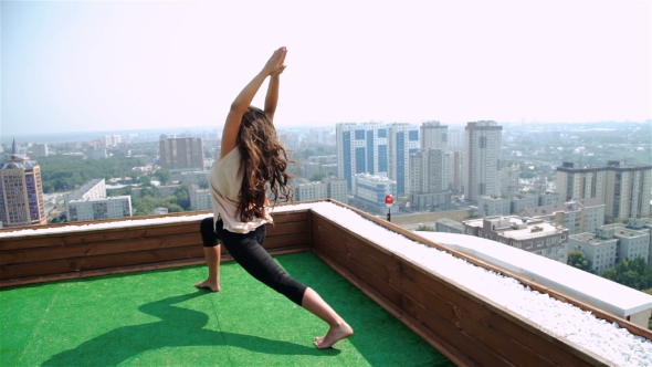 Young Woman Doing Yoga On The Mat On The Roof, Sitting In Lotus Posture.