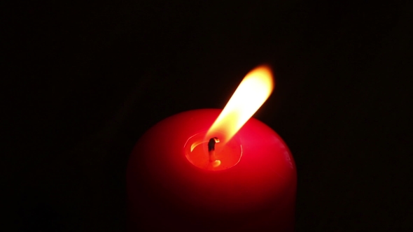 Burning Candle In Red Wax On a Dark Background