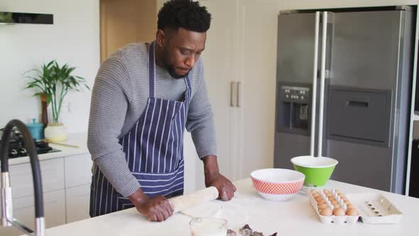 Focused african american man using flour, preparing dough in kitchen