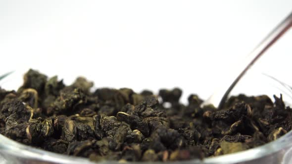 Dried rolled leaves of green tea gunpowder close-up in a teaspoon in a cup