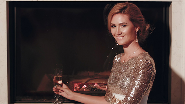 Elegant Woman With a Glass Near The Fireplace
