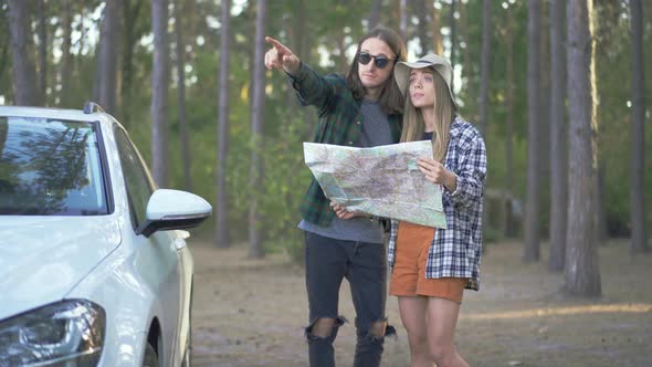 Cute Girl in Hat and Young Man in Sunglasses Staying in the Forest and Trying To Choose the Way