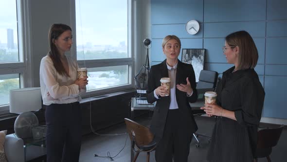 three businesswomen enjoy the girls talk in the office and drinking coffee together at afternoon 