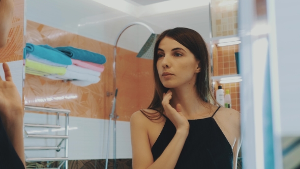 Young Brunette Girl Looking In Mirror In Bathroom. Checking Eyebrows. Beauty.