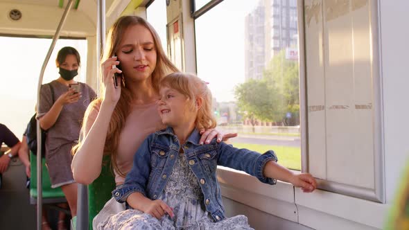 Parent Mother Talking on Mobile Phone Ignoring Little Child Daughter While Sitting in Public Tram