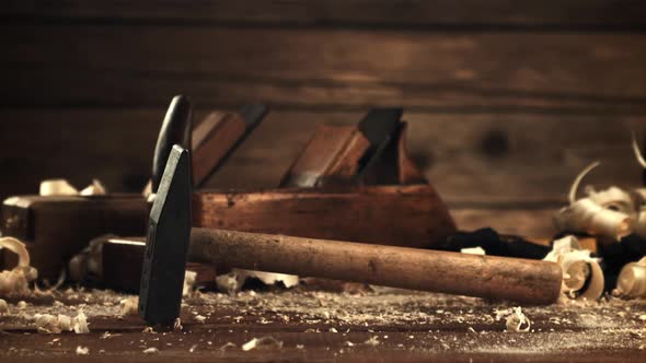 A Hammer Falls on a Table with Wooden Sawdust