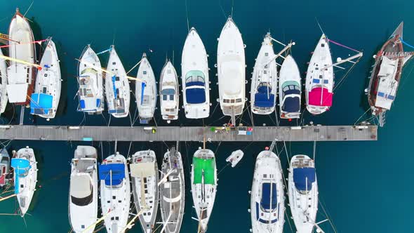 Aerial drone view of Aegean sea port with multiple moored yachts at piers