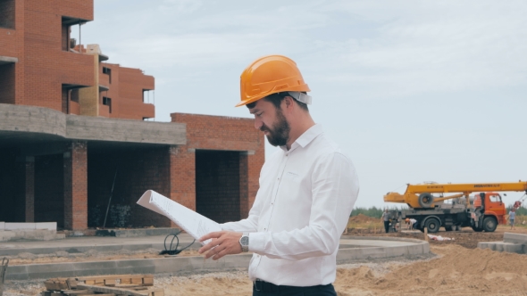 Architect Looking At Blueprints At a Building Site.