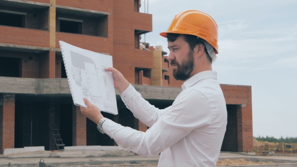 Chief Architect At Construction Site. Chief Architect In a Hard Hat At Construction Site Looking At