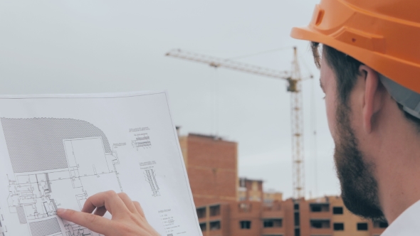 Professional Architect Looking At Blueprints At a Building Site.