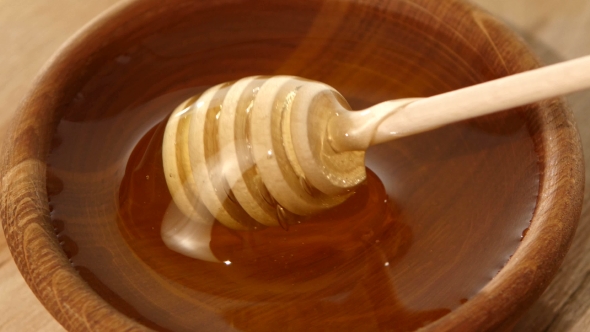 Using Spoon For Honey In Wooden Bowl
