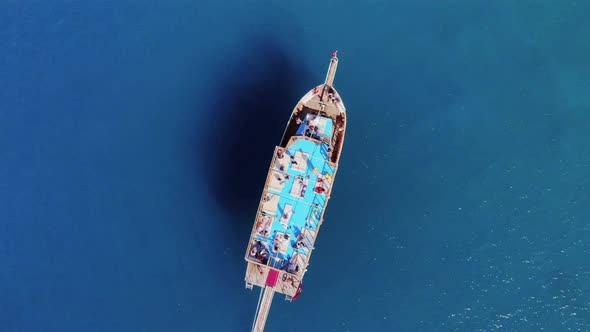 Top View of a Cruise Boat with Tourists on a Deck Among the Blue Transparent Waters of the Sea